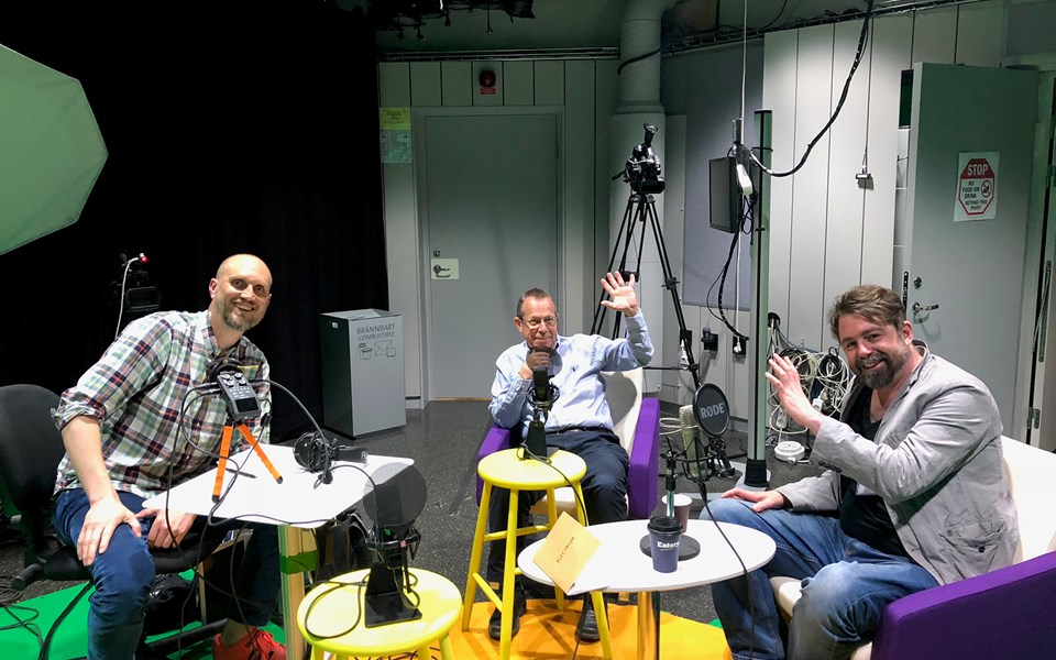 Tre män med mikrofoner i en studio. Inspelning av podd.