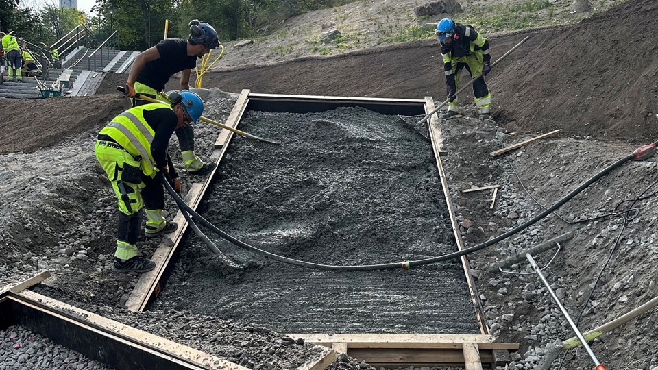 Tre byggarbetare anlägger grunden till en trappa. 