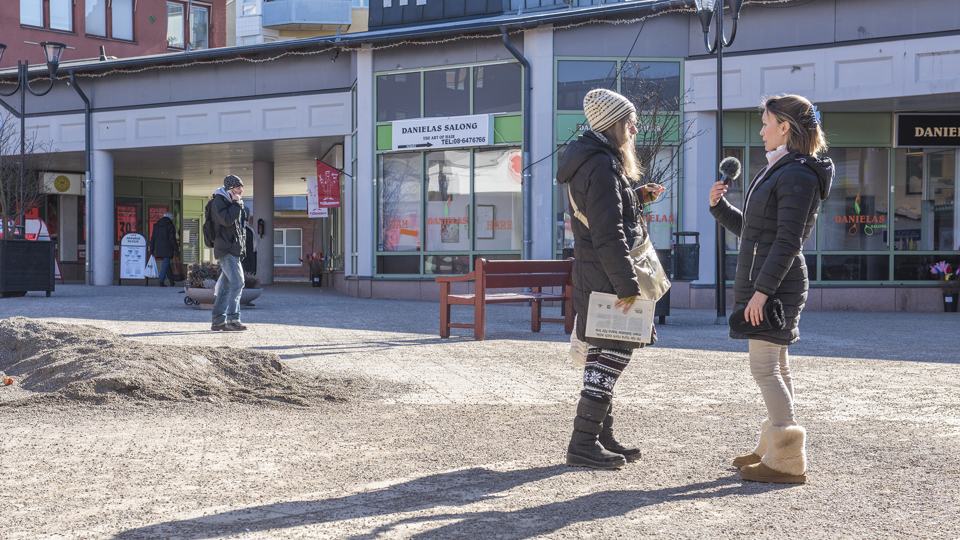 En kvinna intervjuar en kvinna på ett torg.