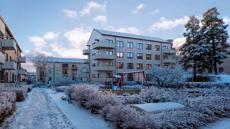 Hus i snö, innergård med lekplats. 