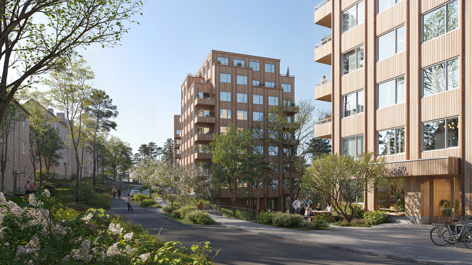 Visionsbild över förslaget sett från den nya gatan. Bilden visar framförallt de två byggnaderna i mitten av förslaget, det västligaste huset skymtas i bakgrunden. Husen är punkthus i trä med indragna balkonger. På de lägre våningsplanen är balkongerna placerade i hörnen. De två översta våningarna har indragna balkonger på husets sidor vilket gör att volymen trappas av uppåt. Den nya gatan visas centralt i bilden. En gångbana går längs gatans högra sida, framför den nya bebyggelsen. På en del av gatan, mellan körbanan och gångbanan finns en planteringsyta. Bakom planteringsytan skymtas en bil, vilket visar att det finns plats för parkering där. Vid planteringsytan, mellan de två byggnaderna, syns räcken och en avsatts i trä vilket är början den föreslagna kopplingen mellan befintligt gångstråk från Gröndalsvägen och den nya gatan. Där finns även en upphöjd övergång över gatan.  