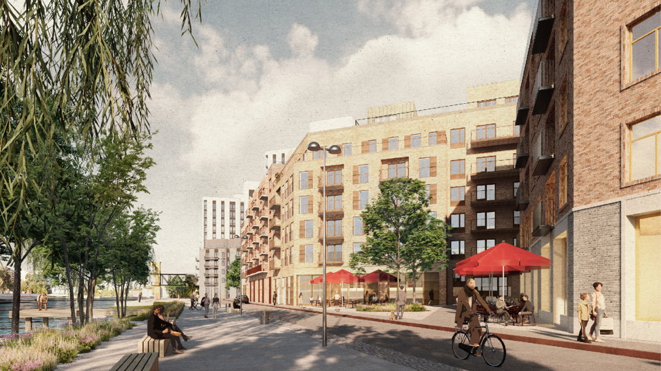 Ett gångstråk längs en kaj. Personer som går och cyklar längs med en gata med sexvåningshus i tegel .