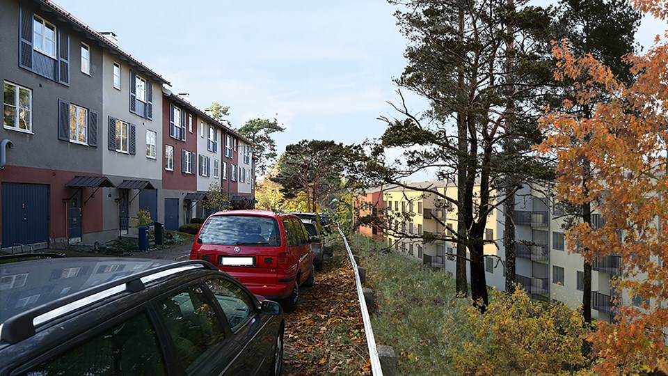 Gata med parkerade bilar utmed flerbostadshus, foto.
