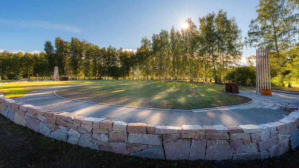 Solen lyser starkt över kistgravområde som ramas in med en låg mur.