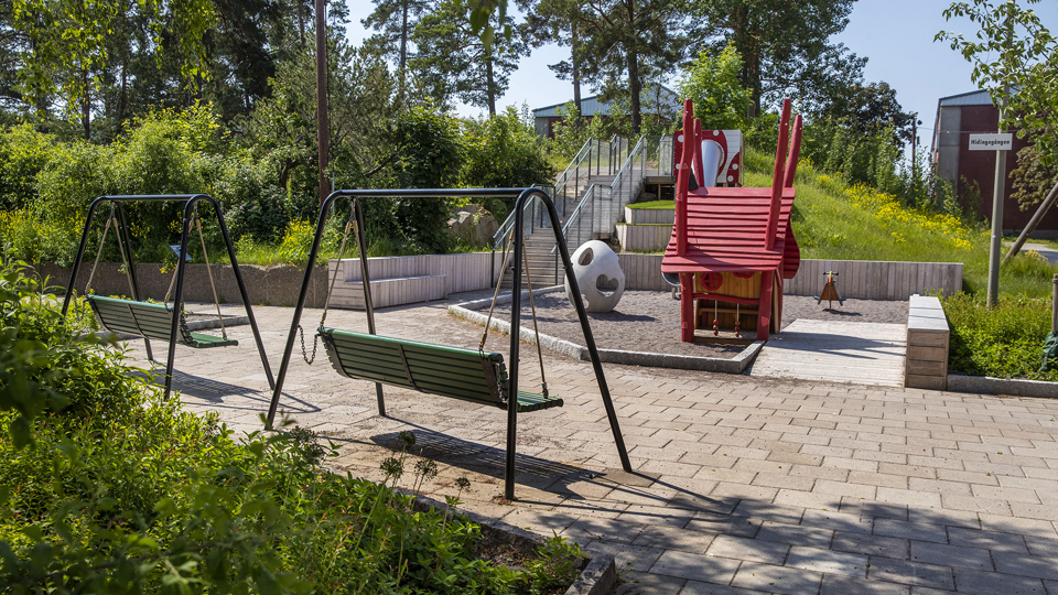 Två hammockar som står mittemot en mindre lekyta med ett lekhus.