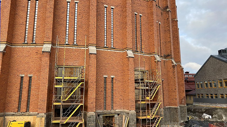 Byggnadsställmingar framför gasklocka. Foto.