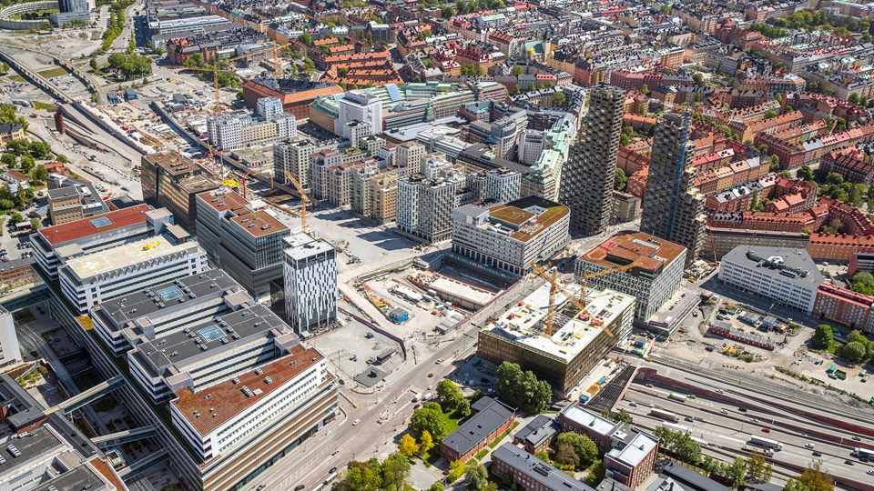 Flygvy över byggarbetsplats med flerbostadshus i stadsmiljö, fotografi.
