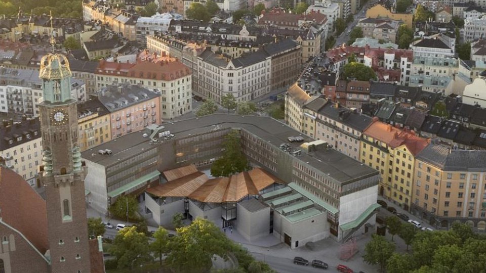 Flygvy över arkitekthögskolan omgiven av hus och träd, fotomontage.