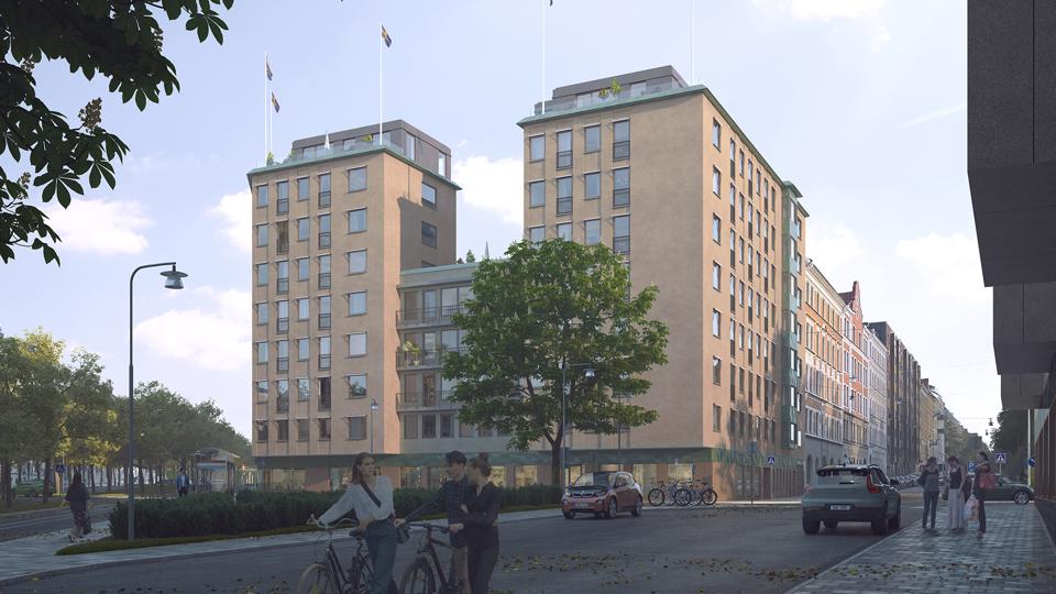 Flerbostadshus sett från marknivå med träd, gata och cyklister. 