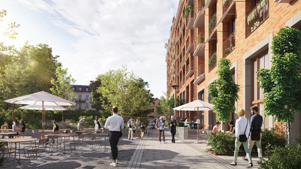 Bild av en del med det nya bostadskvarteret med uteservering och folk som går längs gatan.