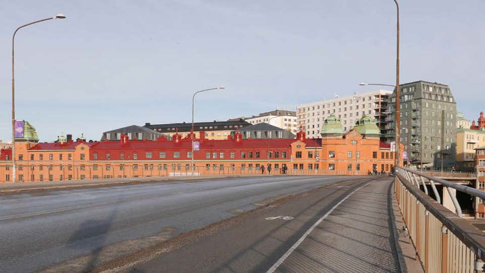 Vy mot byggnader i stadsmiljö, från bro med bil-, gång-, och cykelväg, fotomontage.