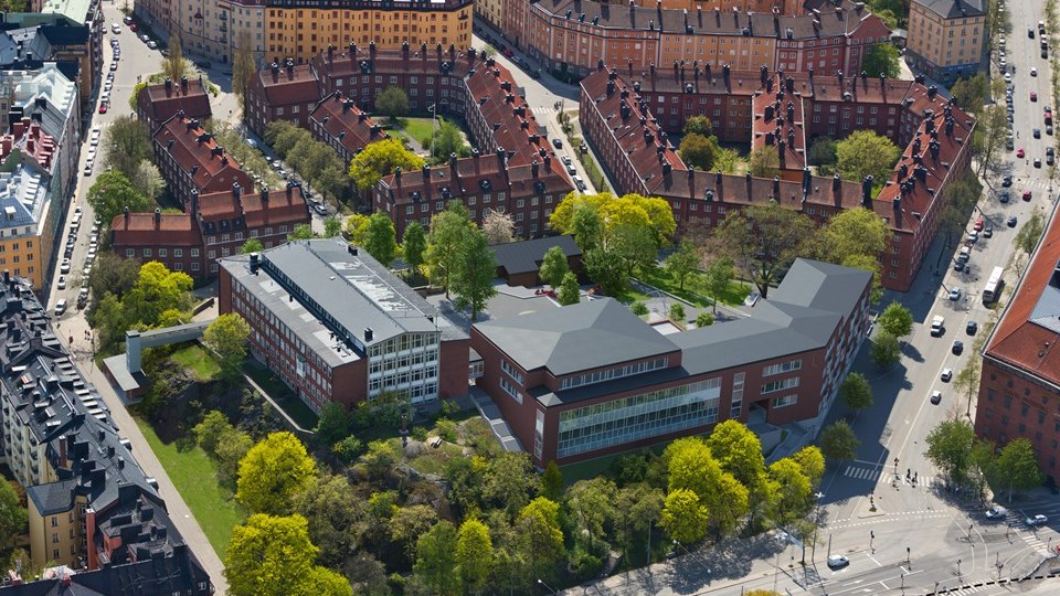 Vy av Rödabergsskolan ovanifrån med omliggande hus, gator och träd, foto.