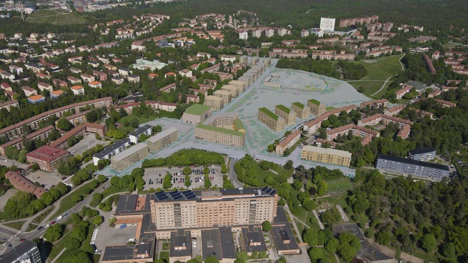 Flygbild över fält med nya och befintliga byggnader. 