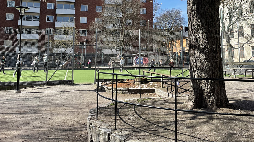 Barn spelar boll vid den inhägnade bollplanen