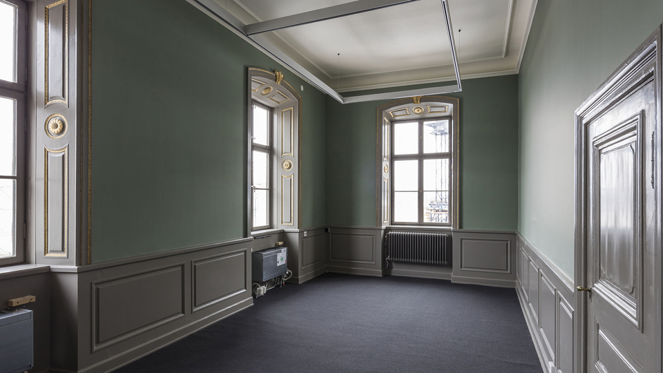 Utställningsrum i Stadsmuseet med gröna väggar och detaljerade fönsterfonder, foto.