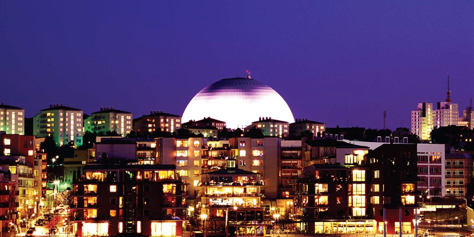 Stadsbild fotograferad på kvällen med Globen upplyst och i fokus.