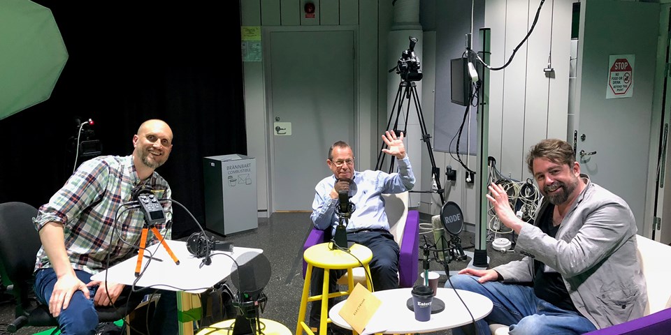 Tre män med mikrofoner i en studio. Inspelning av podd.