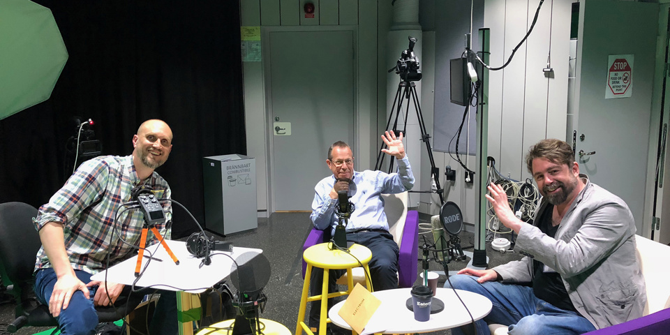 Tre män med mikrofoner i en studio. Inspelning av podd.
