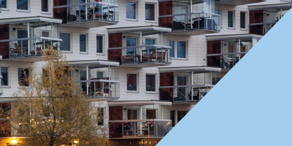 Närbild på ett vitt nyare bostadshus med större balkonger