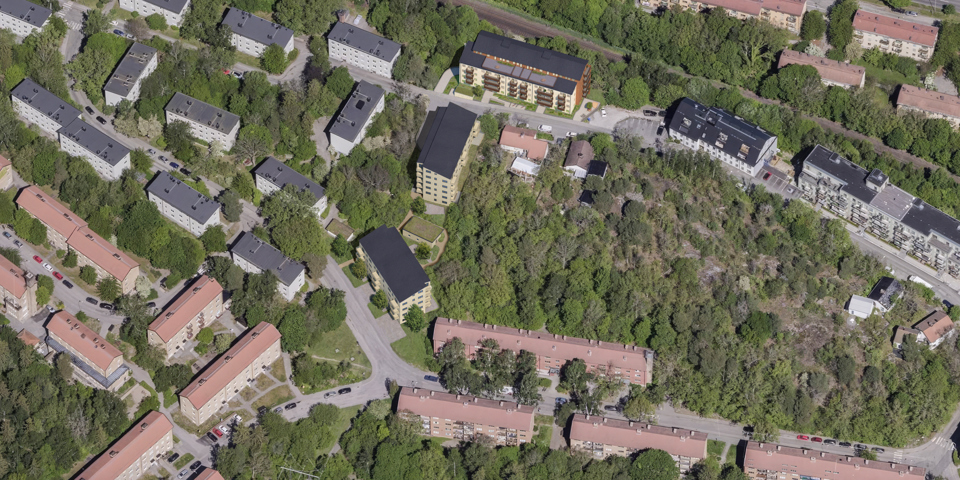 Flygfoto över hela förslaget. De tre nya huskropparna syns ovanifrån i mitten av bilden. Omkring visas befintlig bebyggelse