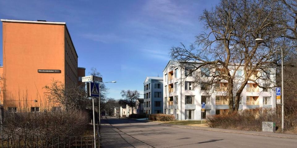 Flerbostadshus till höger, till vänster syns en skolbyggnad, bilväg, fotomontage.