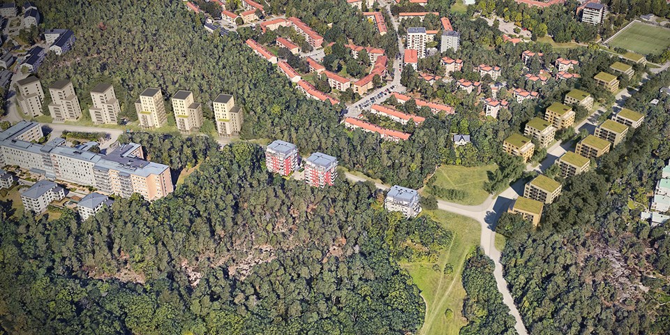 Flygbild över skog och bostadsbebyggelse med både lägre och högre flervåningshus..