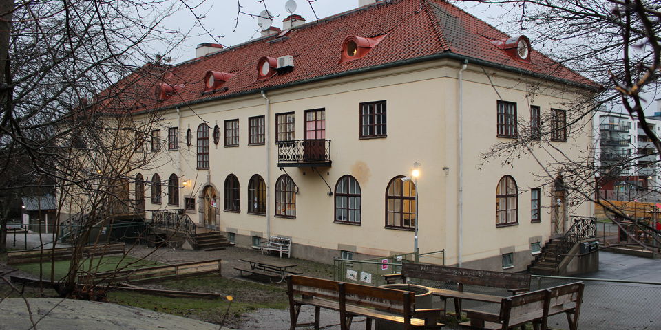 Gul byggnad i två våningar med välvda fönster på första våningen..