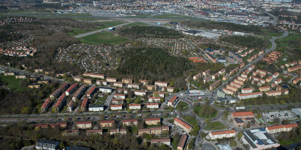 Vy över område med grönområden, vägar och hus. I mitten syns en rondell. 