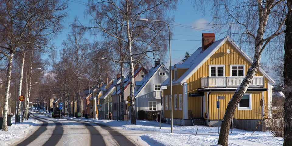 Färgglada trähus längs väg. Soligt vinterlandskap.