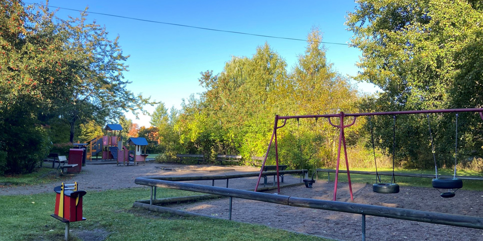 Lekplats med gungor, klätterställning och bänkar.