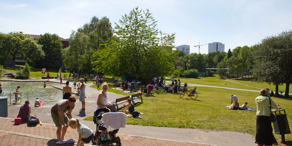 Ett grönområde med plaskdamm. Människor som umgås och badar, foto.