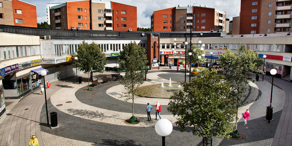 Runt torg med fontän i mitten fotat ovanifrån. Flervåningshus i bakgrunden., foto.