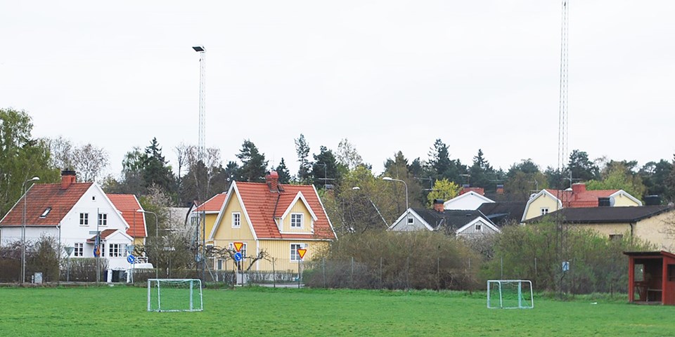 Villor som ligger vid en fotbollsplan och som är omgivna av träd. Foto.