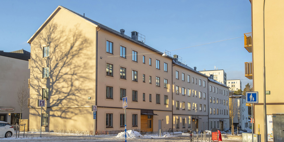 Ett lamellhus i fyra våningar med sadeltak, fotografi.