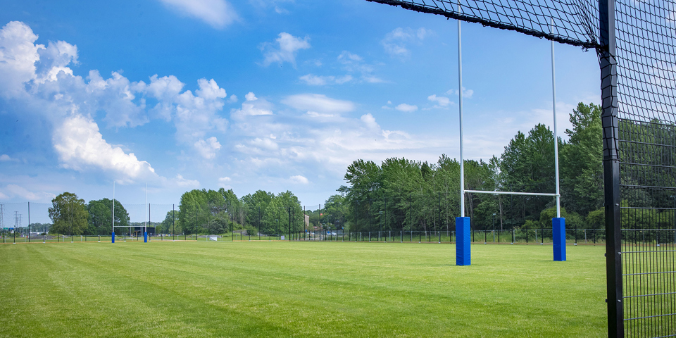 Rugbyplan med naturgräs och rugbymål, foto.