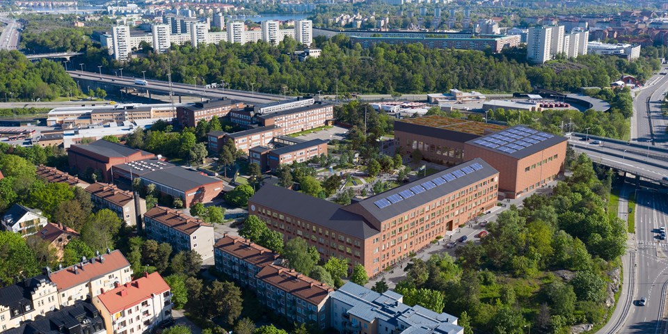 Flygbild som visar den nya skolbyggnaden och idrottshallarna och omgivningarna med bostäder, vägar och grönska. Illustration/foto