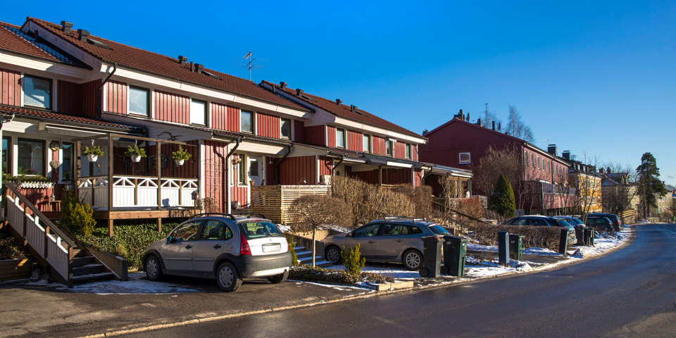 Kedjehus invid väg. Bilar finns parkerade framför husen, foto.