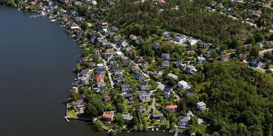 Flygvy över bostadshus, grönområden och vatten, foto.