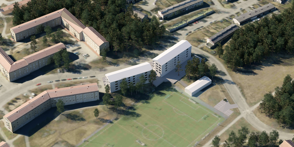 Flygfoto taget snett uppifrån där de nya flerbostadshusen och en stor bollplan visas.