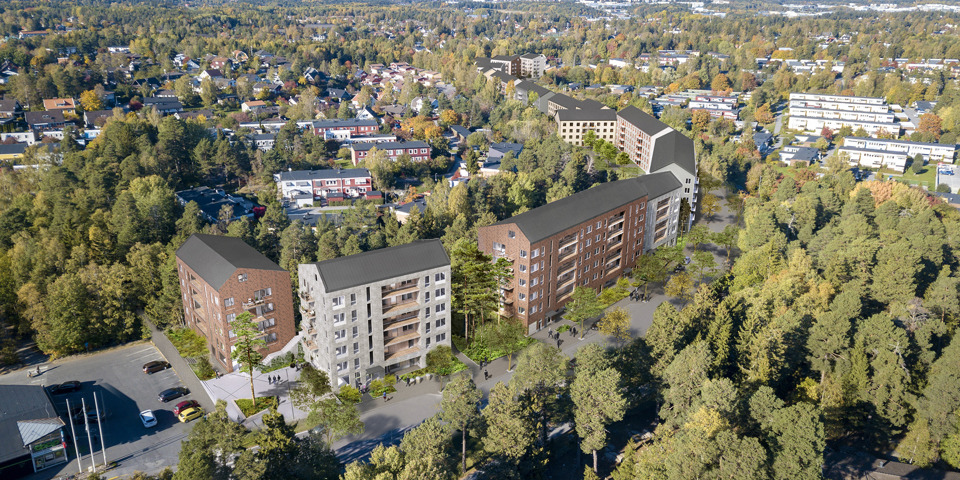 Ett flygfoto där man ser höga hus och radhus, vägar och trädkronor.