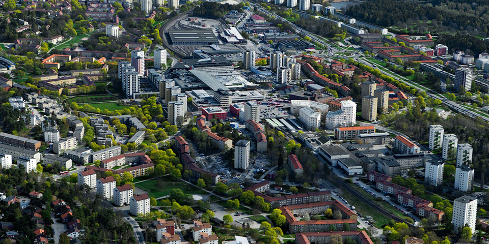 Små och stora bostadshus. Träd och gräsmattor. Foto.