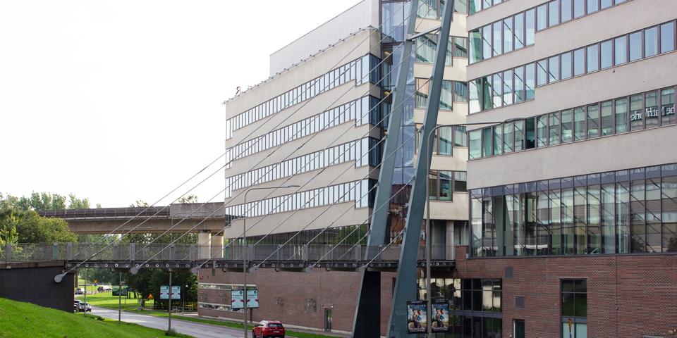 Bro över bilväg som leder till en byggnad, fotografi.