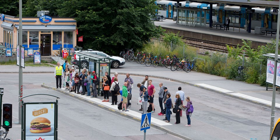 Människor i kö vid busshållplats i Spånga centrum, foto.