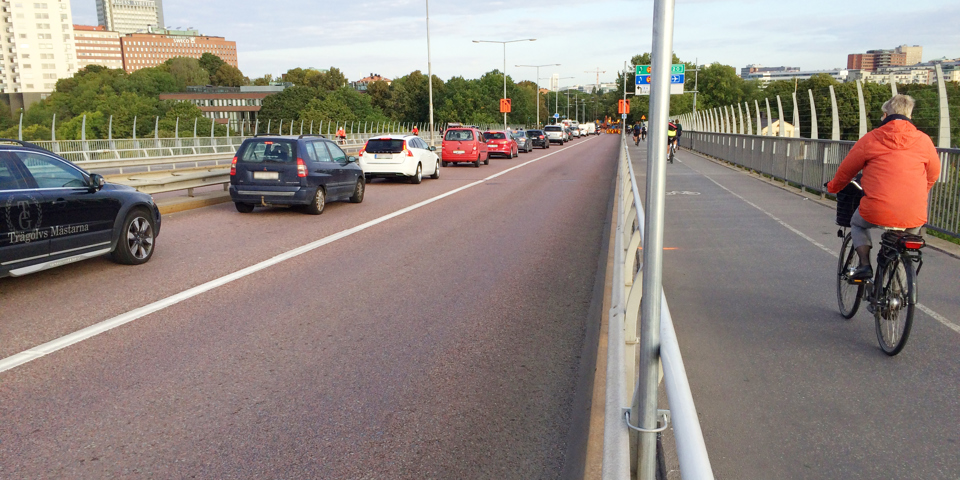 Bro med bilväg och cykelbana. Cyklister som cyklar och bilar som kör, foto.