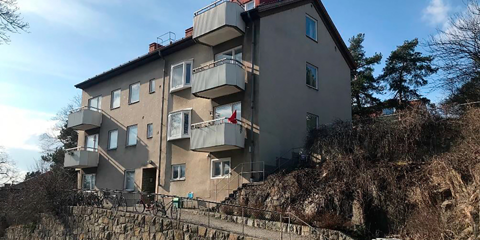 Bostadshus med 3 våningar och balkonger som ligger på höjd.  Foto.