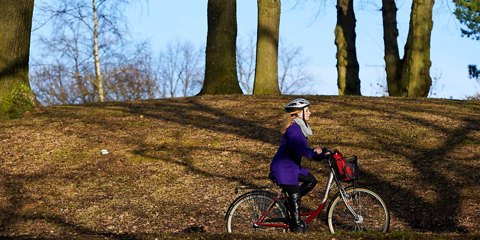 Kvinna på cykel i naturen. Foto.