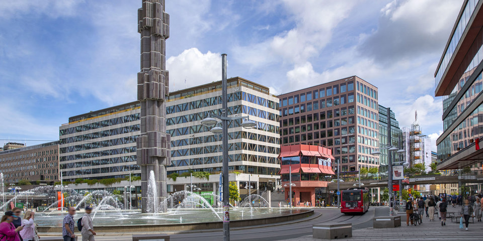 Foto över Sergels torg med statyn och fontänen vid rondellen.