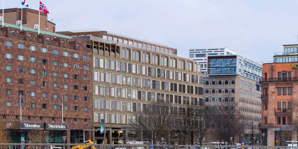 Fasaderna till fyra stora kontorsbyggnader i grått och tegelfärg. Ett av husen har svenska, franska och norska flaggan på taket. Framför husen syns en trafikerad väg.