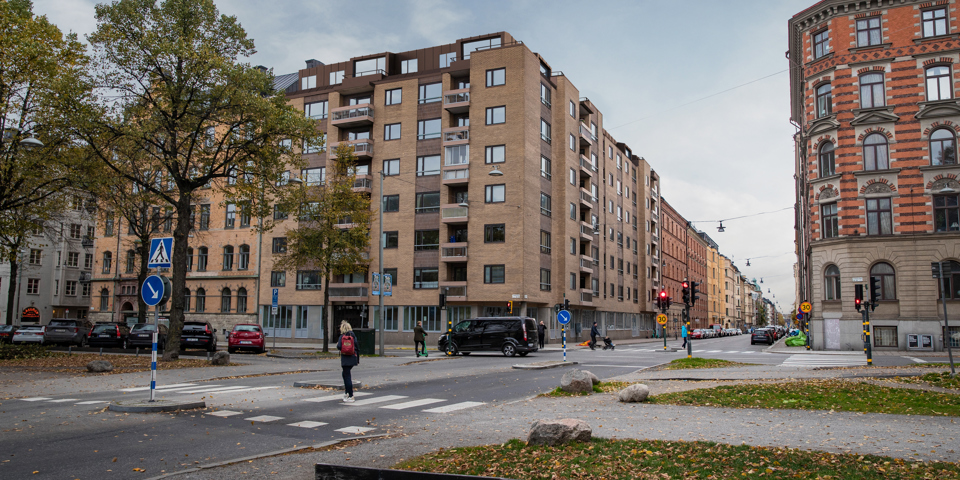 Bostadshus i tegel, träd och människor i rörelse som går mellan alléerna. Visualisering.