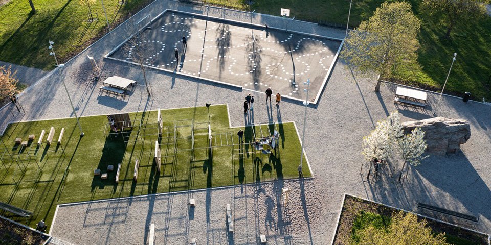En park med banor för klättring, lekytor och sittmöbler. Foto taget ovanifrån.